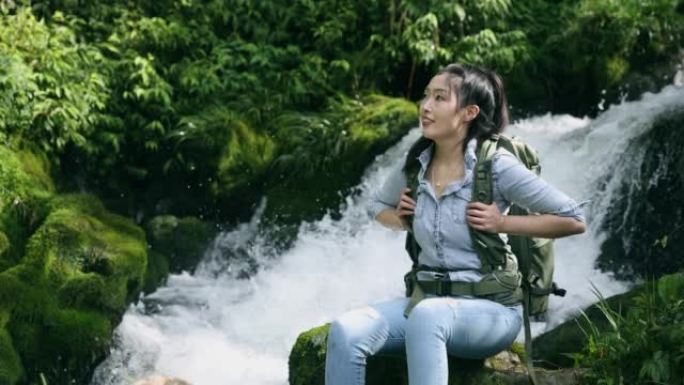 女性徒步旅行者坐在大自然的瀑布旁
