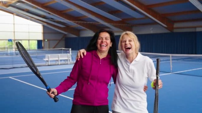 两名激动的成熟女子网球运动员在室内球场上的肖像