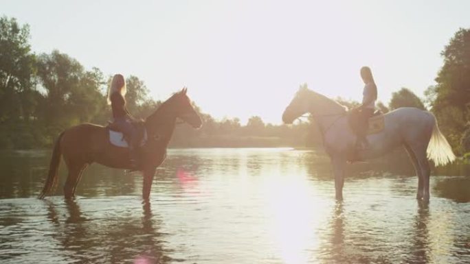 镜头耀斑两个骑手坐在河边的马匹上看着相机