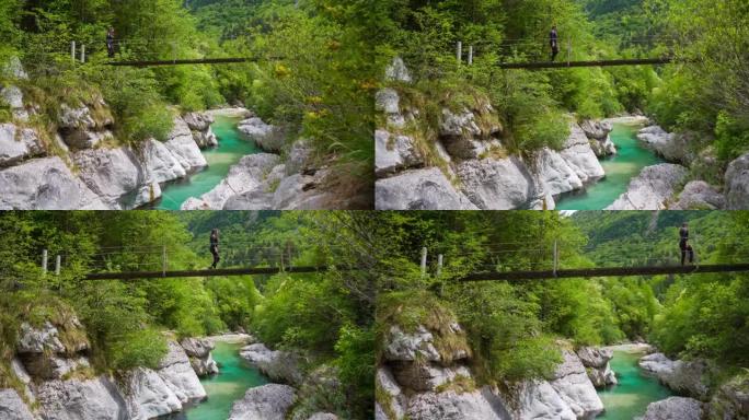 在阳光明媚的日子里，女游客在山溪峡谷上的一座木桥上徒步旅行