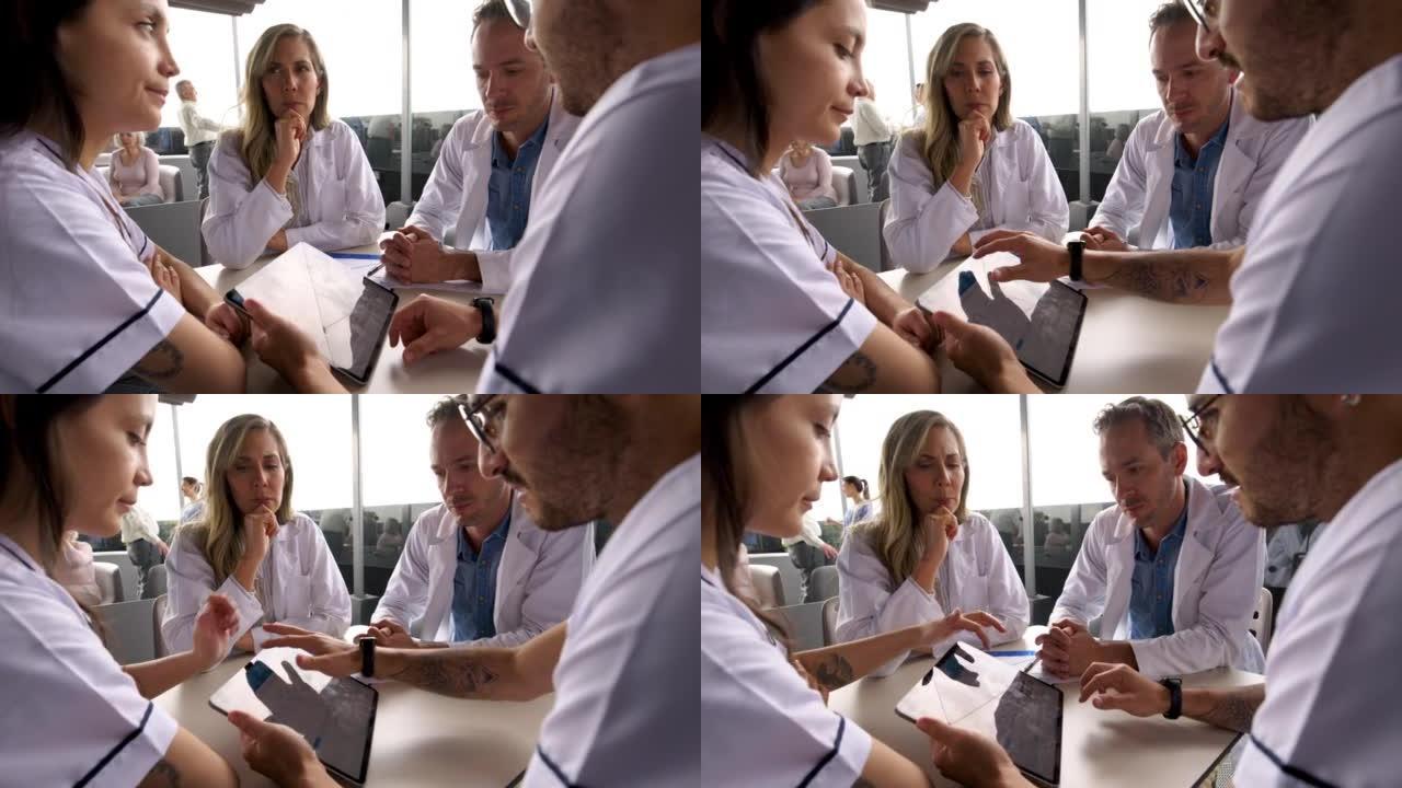 医护人员团队在喝咖啡休息时在自助餐厅的平板电脑上查看医疗图表时讨论了一个病例