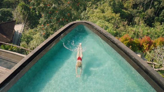 顶视图性感女人在热带酒店水疗中心无限泳池游泳，丛林景观享受异国情调的暑假4k奢华生活方式