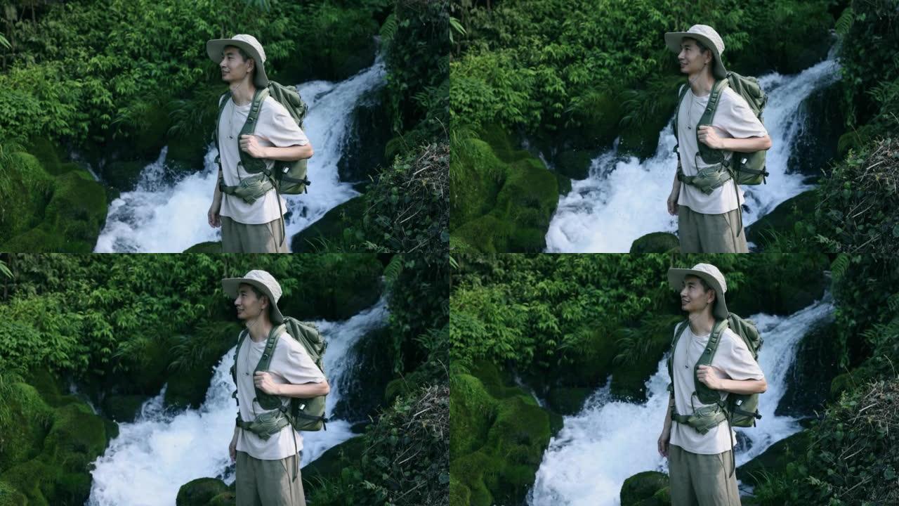 年轻人站在山上的瀑布旁徒步旅行