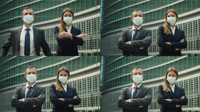 在冠状病毒大流行的社交距离期间，商业伙伴或同事戴着防护医用口罩在镜头前微笑着，对他们在摩天大楼背景上