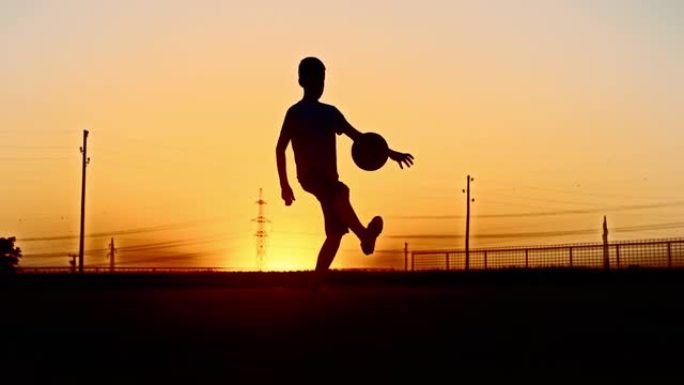 男孩在黄昏时在野外玩足球