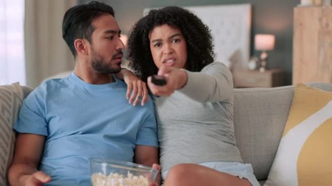 争吵夫妇，电视遥控器和控制女人换频道看电影，在家里的沙发上吃爆米花。战斗，生气和沮丧的男人在看体育比