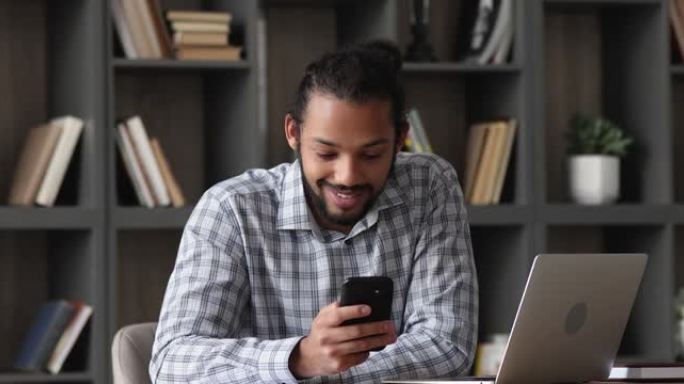非洲人坐在办公桌前使用智能手机分享短信