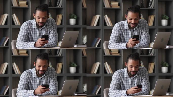 非洲人坐在办公桌前使用智能手机分享短信