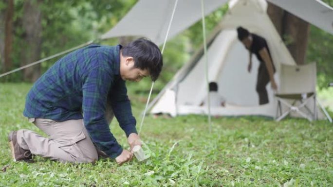 亚洲男性露营者与家人一起准备帐篷