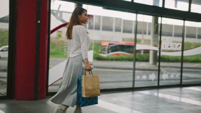 年轻女子背着购物袋走在购物中心