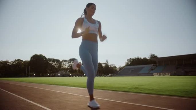 浅蓝色运动上衣的美丽运动员在户外体育场跑得非常快。她在一个温暖的夏日下午冲刺。精女正在慢跑训练。慢动
