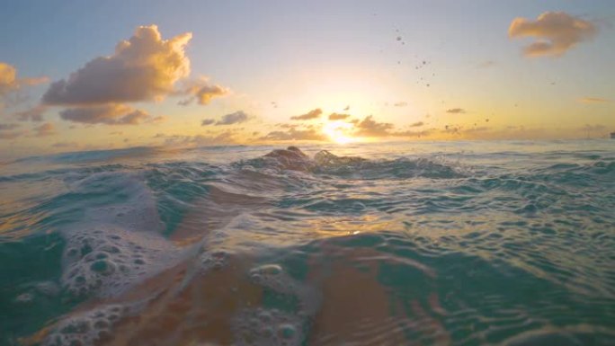 POV: 在绿松石海洋中游泳的年轻女子踢脚并观看日落