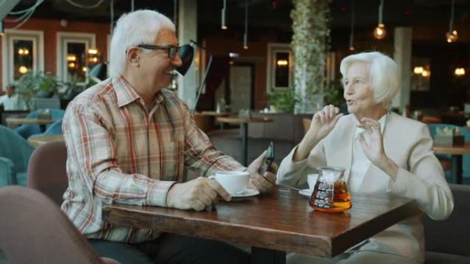 美丽的老年夫妇在咖啡馆的餐桌上说话和打手势的慢动作