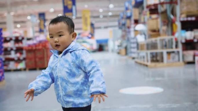 男婴在supermaket中散步和购物，使他的父母流淌