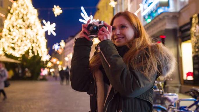 微笑的女人在装饰精美的城市享受圣诞精神，拍照