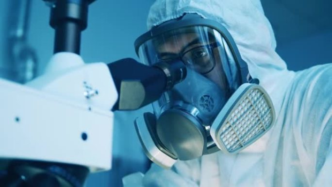 穿着防护服的实验室工作人员正在使用显微镜