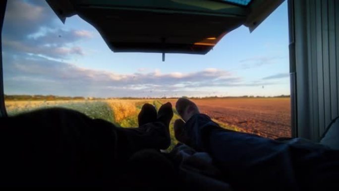 POV夫妇躺在汽车后面，看着农村地区的热气球