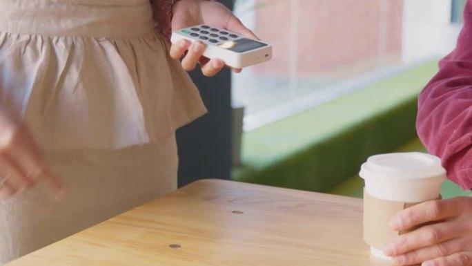 使用借记卡或信用卡在咖啡店进行非接触式购物的人的特写