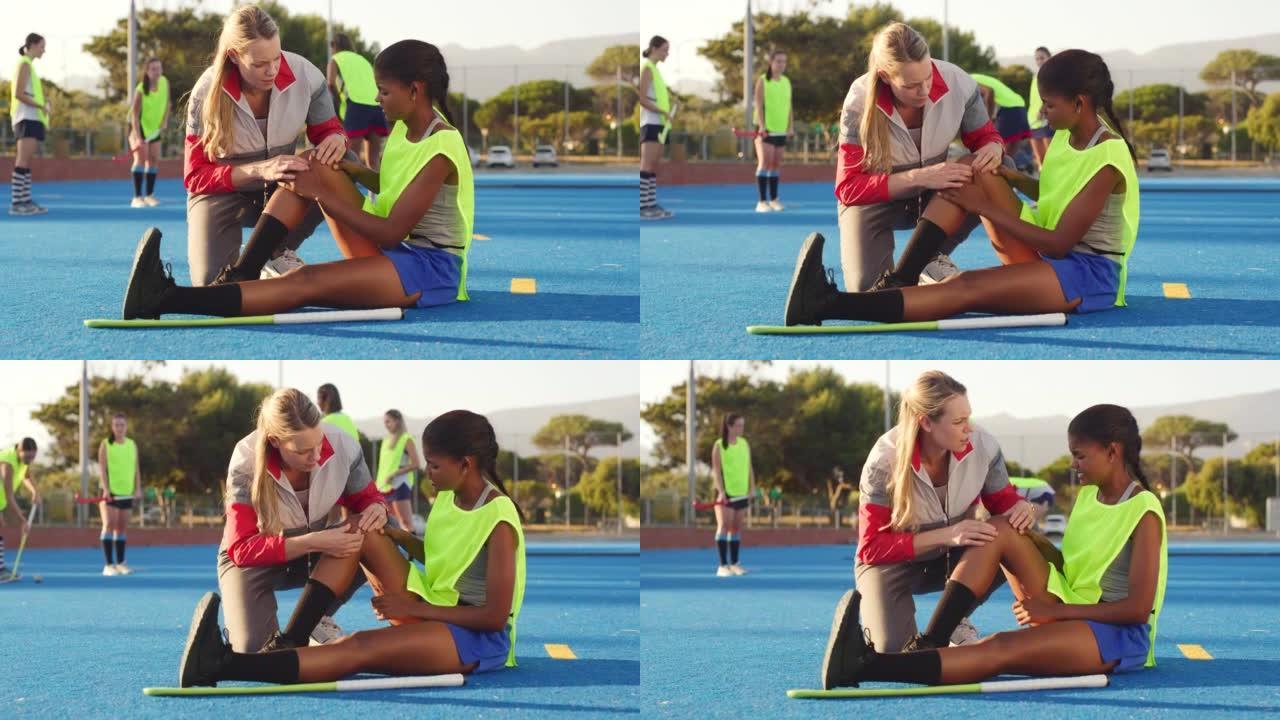 全长曲棍球教练帮助膝盖疼痛的受伤学生。高中体育运动员在野外练习中受伤。教练摩擦，按摩和治疗扭伤的学生