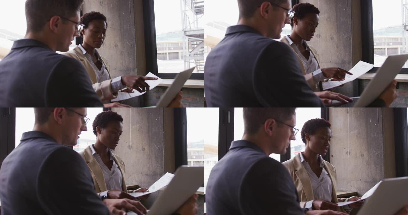 坐在咖啡馆里聊天的男女商业同事看着笔记本电脑和文书工作