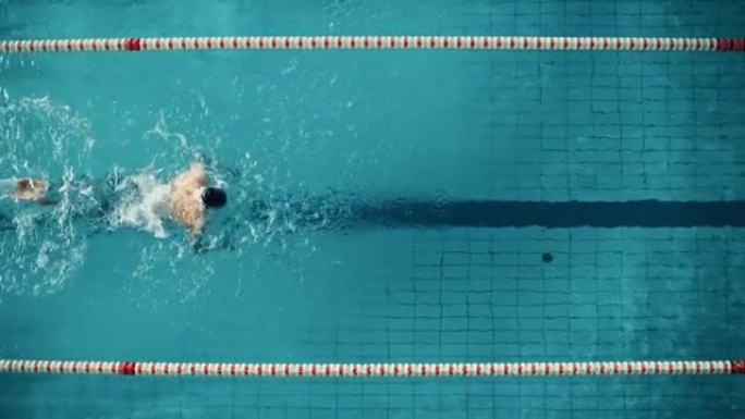 空中俯视图男游泳运动员在游泳池游泳。专业运动员为冠军进行训练，运用蝶泳技术，努力和取胜的决心。电影范