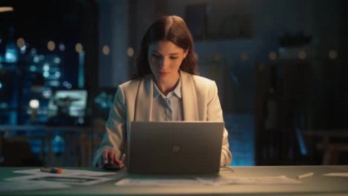 晚上在公司办公室工作的漂亮女性在笔记本电脑上工作。年轻的秘书分析报告。营销助理为客户制定营销策略。