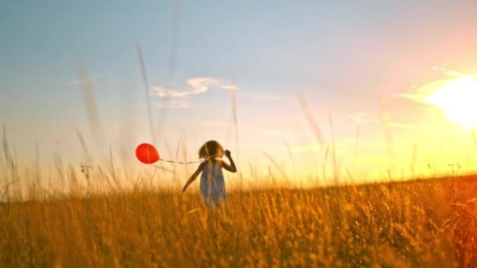 超级SLO MO女孩在日落时在草地上奔跑时拿着一个红色气球