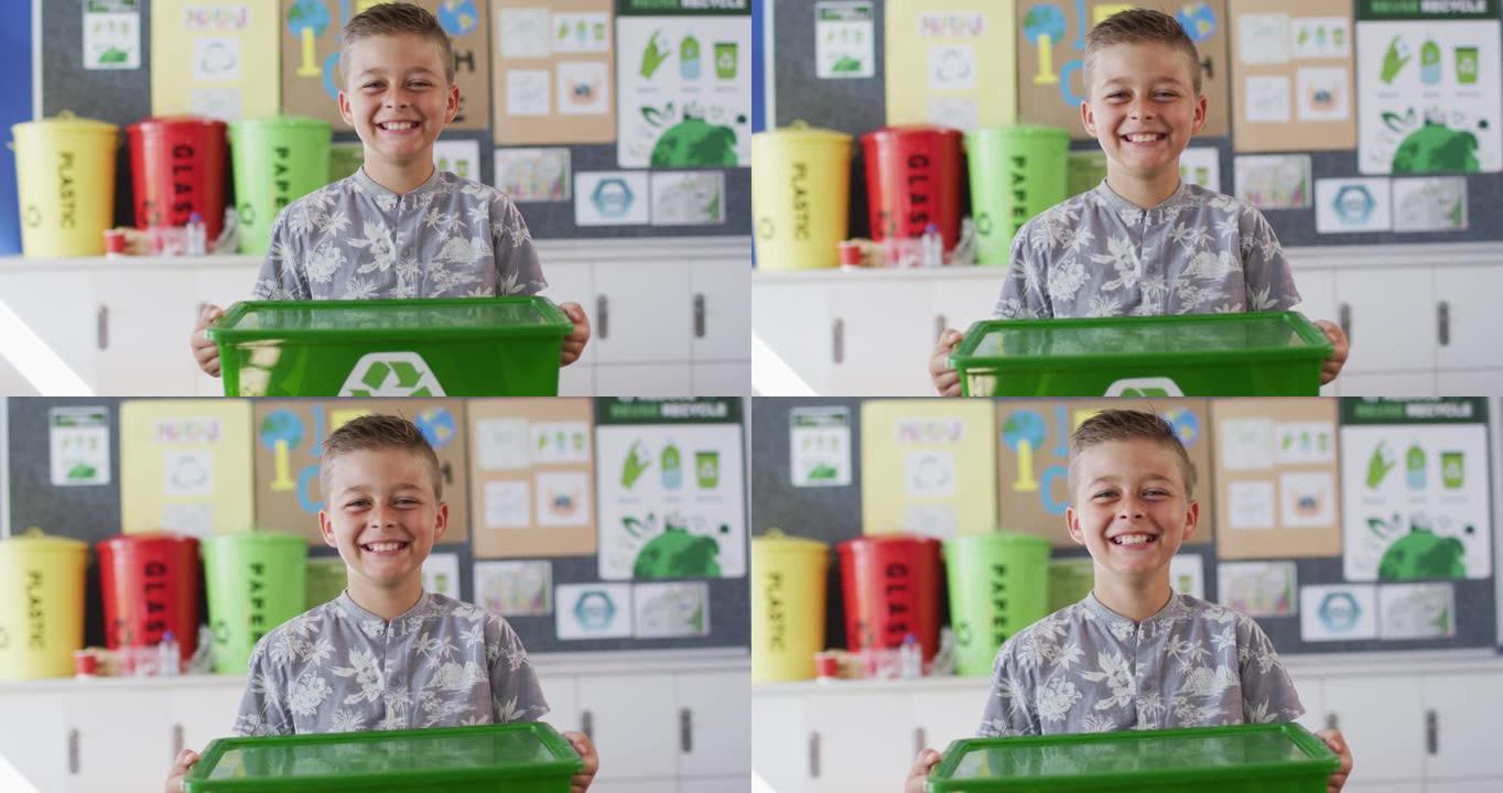 白人男生微笑着，拿着回收箱，站在教室里