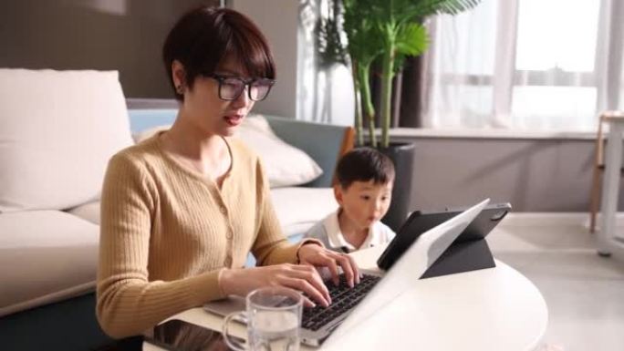 母亲和儿子一起在家工作，一起使用平板电脑