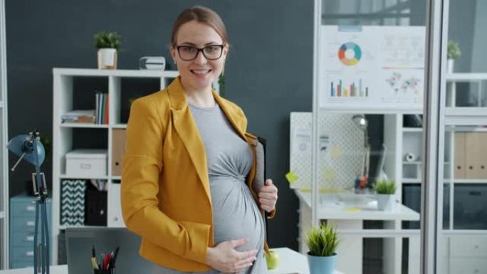 成功的孕妇站在工作场所微笑着看着相机的肖像