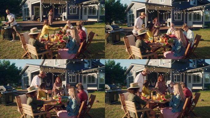 父母，孩子和朋友聚集在美丽家园外的烧烤餐桌旁。老人和年轻人玩得开心，吃喝。后院的花园派对庆祝活动。