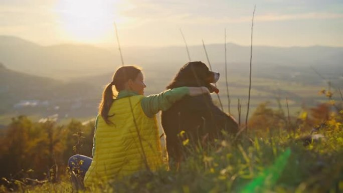 日落时分，SLO MO女人与她的狗在山顶上结为纽带