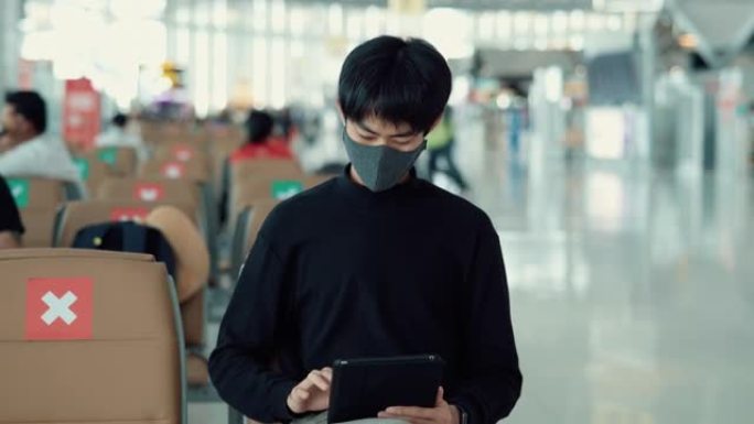 游客男子坐在机场时戴口罩保护