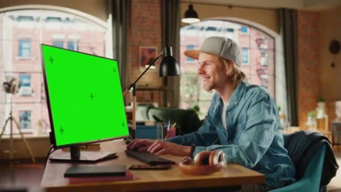 年轻英俊的男人在家工作，在带有绿屏模拟显示的台式计算机上。成功的男性收到积极的消息并庆祝胜利。学生获