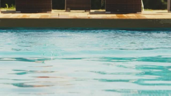暑假期间，一对夫妇在游泳池旁，男子潜入水中