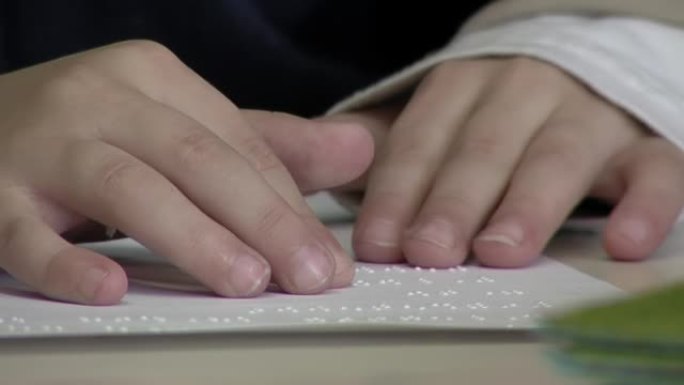 在阿根廷的一所公立学校为盲人和视障儿童学习使用盲文字母的孩子的手。特写。