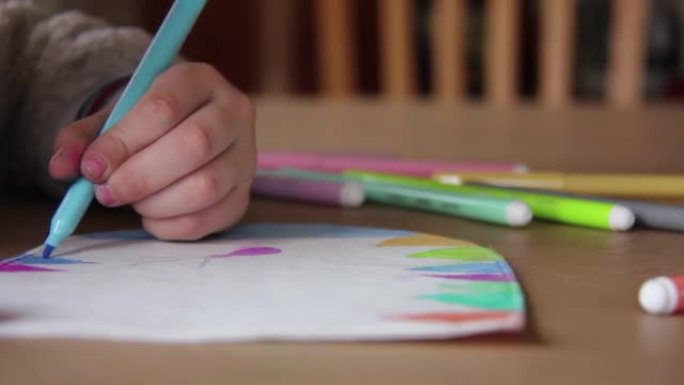 女孩在桌子上在纸上画画，小女孩在家里用彩色标记在纸上画画。特写。4k分辨率。