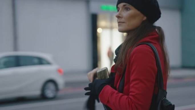 穿着红色外套的女士在使用智能手机等待乘车时戴上手套