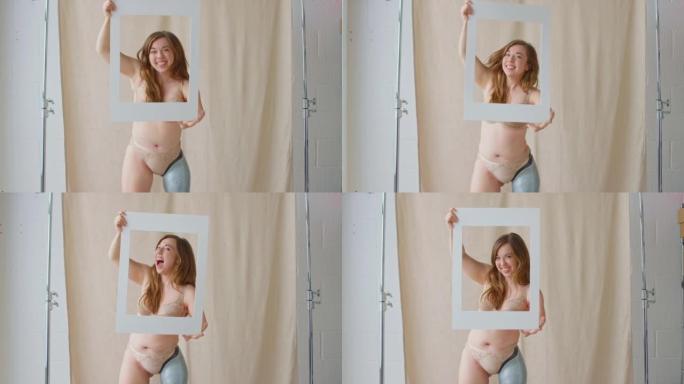 工作室拍摄的自信而积极的女性假肢透过纸板相框拉着有趣的脸-慢动作拍摄