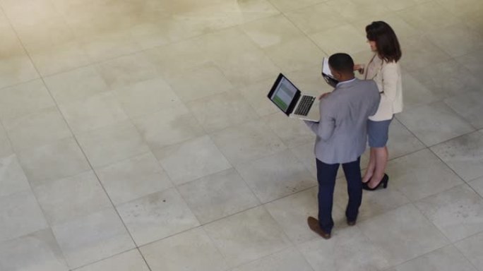 多元化的商人和女商人在现代办公室的大厅里聊天和使用笔记本电脑