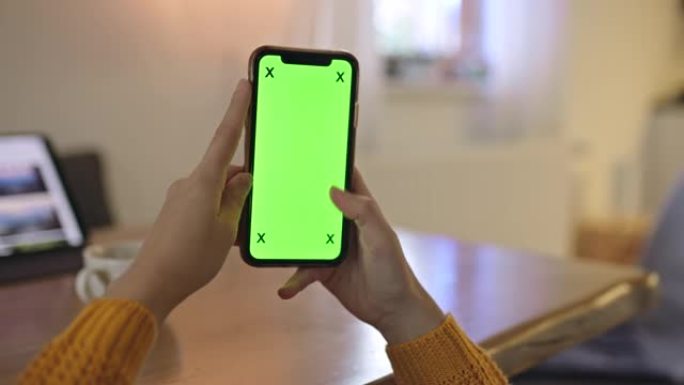 女士无法辨认的女人在家中使用带有色度键绿屏的智能手机