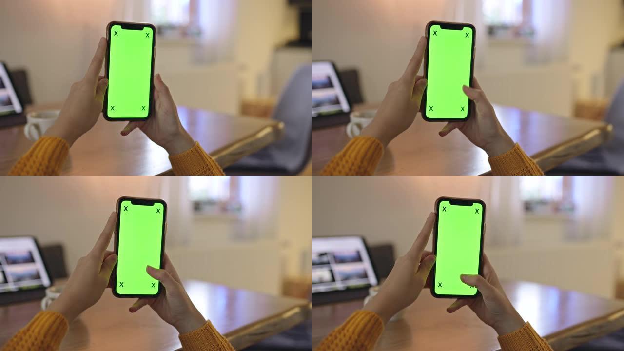 女士无法辨认的女人在家中使用带有色度键绿屏的智能手机