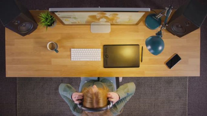 女性平面设计师或照片润饰师的俯视图在晚上坐在创意办公室的电脑屏幕上使用图形平板电脑的办公桌前戴上无线