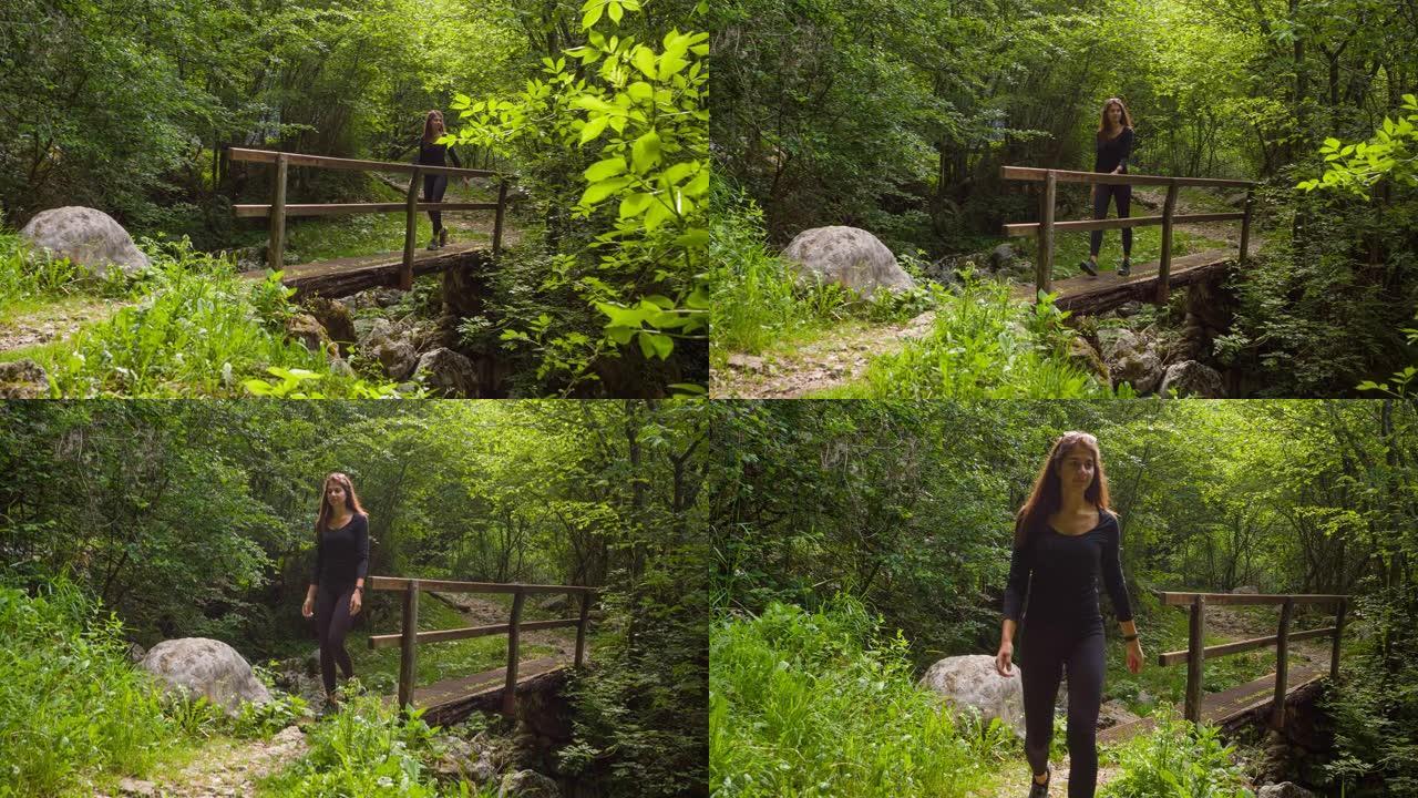 适合在大自然中穿过溪流桥在户外行走的女人