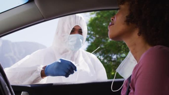非裔美国妇女，在户外由医务人员坐在车里做covid测试