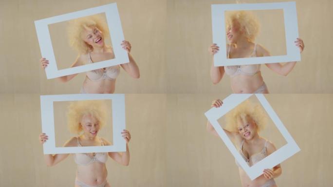 工作室拍摄的自信和积极的年轻白化病妇女微笑，并通过纸板相框-拍摄慢动作