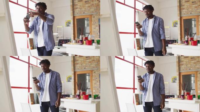 非裔美国男艺术家在art studio用智能手机拍摄画作