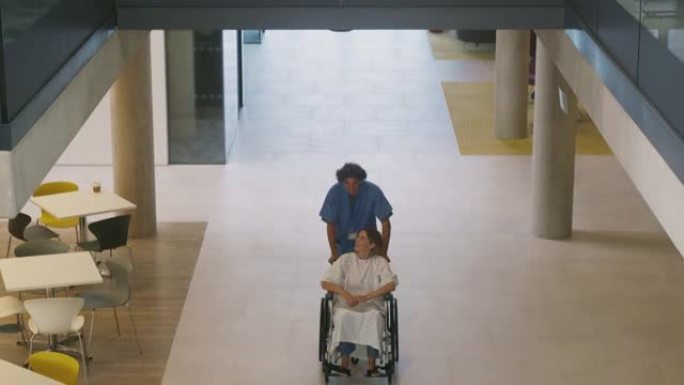 摄像机从讨论扫描的医生追踪到在医院坐轮椅的病人