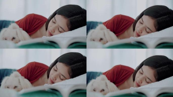 年轻女子躺在床上睡觉，小狗躺在床上休息。与拥抱的狗一起小睡