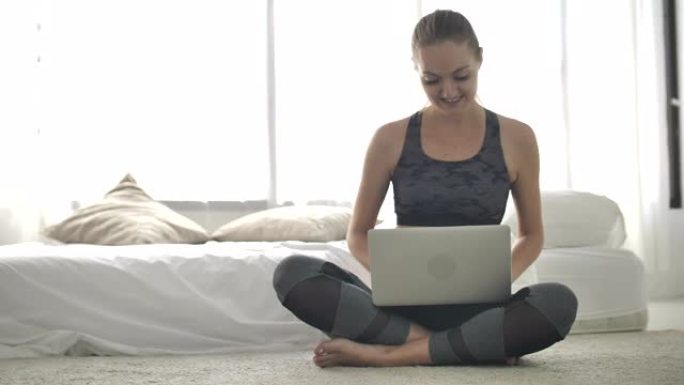 运动妇女使用计算机笔记本电脑在互联网上学习瑜伽